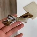 Détail de la barrette à cheveux nœud en acétate ambré avec gravure logo fait main - Marbre Gris-Beige