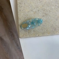 Detalle de pinza para el pelo a cuadros azul claro con elegante incrustación de metal dorado - Óvalo Azul
