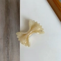 Macro detail of acetate bow hair clip with creamy marble texture and sparkling rhinestone - Beige