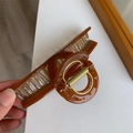 Detail van amberkleurige haarklem van acetaat met sterke gouden metalen veer - Karamel
