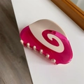 Macro shot of rose pink acetate hair claw with cream swirl pattern and metal spring - Red Vortex