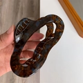 Macro detail of large acetate hair claw clip with dark amber tortoiseshell pattern - Retro Floral