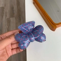 Detalle de pinza para el pelo tipo lazo en denim azul con lunares rojos mostrada en la mano - Azul Denim con Lunares Rojos