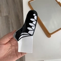Macro-opname van zwart-witte acetaat haarklem in de vorm van een canvas sportschoen - Zwart en wit haarklem