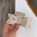Detail of a cream bow hair claw clip featuring a rhinestone smiley face decoration - Cream White
