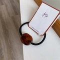 Detail of high-elastic black hair tie featuring a polished brown amber textured resin bead - Deep Caramel
