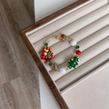 Dettaglio del bracciale natalizio con perline a forma di alberi rossi e verdi in scatola - Stile pino