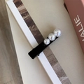 Dettaglio del fermaglio in velluto nero con tre perle graduate su uno sfondo minimalista - Stile Tre Perle