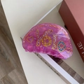 Dettaglio di un fermaglio per capelli sfumato con strass colorati e scritte yolo incise - Stile Viola Y