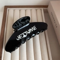 Macro shot of black glossy hair claw featuring 3D white JE T'AIME lettering detail - 11cm x 4.3cm / Black
