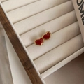 Gros plan de boucles d'oreilles cœur rouge plaquées or sur support en velours crème - Boucles d'Oreilles Cœur Rouge (QYG3047) / Or