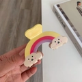 Vue détaillée d'une pince à cheveux arc-en-ciel avec des nuages souriants sur un bureau - Petit / Jaune