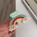 Gros plan détaillé d'une pince à cheveux arc-en-ciel avec nuages souriants aux extrémités - Petit / Vert