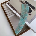 Detailaufnahme der grobzinkigen Acetat-Haarkämm mit mintgrüner Marmorierung auf einem Kunstbuch - Irisierendes Grün