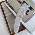 Detailed macro view of the pearlescent acetate hair comb with smooth teeth and ergonomic handle - Iridescent White