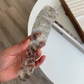 Macro shot of the pearlescent marble texture and wide teeth on the acetate hair comb - Gray