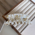 Vue détaillée d'une grande pince à cheveux marbrée posée sur un support à bijoux en bois - Marbre Crème