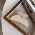 Vue macro d'une pince à cheveux papillon en acétate crème avec des strass étincelants - Beige