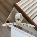 Vista detallada de pinza para el cabello de acetato jaspeado sobre bandeja de madera - Mármol Crema
