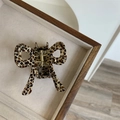 Macro view of leopard print bow hair claw made of acetate on a beige velvet tray - Coffee Polka Dot