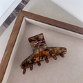 Primo piano di una pinza per capelli in acetato con motivo a guscio di tartaruga scuro - Texture Marrone