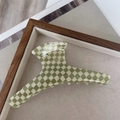 Gros plan d'une pince à cheveux à damier vert et beige sur un plateau en bois - Carreaux Vert