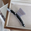 Close-up of marble pattern acetate hair claw clip on wooden jewelry display tray - Black Texture