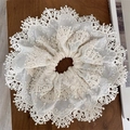 Eleganter weißer französischer Spitzen-Scrunchie mit Stickerei auf Holzoberfläche - Spitzenrüschen-Stil / Gebrochenes Weiß