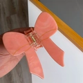 Dettaglio di una pinza per capelli in acetato con motivo marmorizzato rosa a fiocco - Marmo Rosa