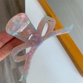 Detailaufnahme einer Haarklammer in Schleifenform mit buntem Marmor-Acetat-Muster - Pfirsichrosa