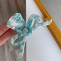 Detailansicht der Haarklammer mit blauer Marmorierung und Schleifen-Design in der Hand - Hellblau