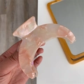Detailed macro view of large crescent acetate hair claw with pink marble texture finish - Crescent Moon