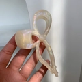 Detail of a large bow hair claw clip made of iridescent cream acetate with strong grip - Beige Texture
