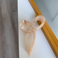 Macro shot of high-quality acetate hair claw clip with bow design and metal spring - Caramel Texture