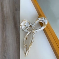 Detailed top view of a large acetate bow hair claw clip with cream marble texture finish - Rice Flower Texture