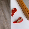 Vue détaillée de pinces à cheveux piment en acétate rouge marbré avec attaches dorées - Sandwich Au Chili