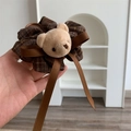 Dettaglio di elastico scozzese marrone con testa di orsetto di peluche e fiocco in raso - Caffè Quadri