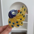 Primer plano de pinza de pelo de pavo real en acetato de colores sostenida a mano - Pinza Pavo Real Amarillo