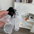 Detail of large white lace flower hair tie with black satin elastic band macro shot - White