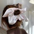 Detail of a large satin bow hair scrunchie with pink ribbon pattern on cream fabric - 20cm Size