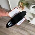 Minimalist black oval hair clip with white nyunyu lettering on a brand display card - Black Oval
