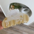 Detail van een beige crèmekleurige haarklem van acetaat met eenhoornreliëf en spiraalpatroon - Eenhoorn / Beige En Wit Rennende Eenhoorn Stijl