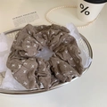 Detail von kaffeebraunem Haargummi mit weißen Schleifen und Punkten im Silberkorb - Graubraun Schleife Scrunchie