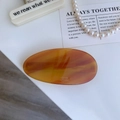 Détail d'une barrette ovale vintage en acétate avec texte Barrette La France gravé - Café Clair