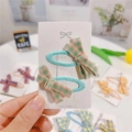 Close-up of a pair of blue plaid bow hair clips on a white card display for girls - Green and Pink Plaid