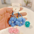 Detalle de gomas para el pelo de flores azules con perlas en un cartón de papel blanco - Azul