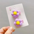 Close-up of two purple plush flower hair clips with yellow center and pink ribbon wrapped base - Light Purple Duckbill Clip
