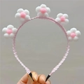 Detail of pink plush sunflower headband with soft macaron balls on a wavy hairband - White