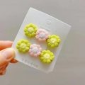 Detail showing two crochet daisy hair clips in pastel pink and green on a display card - Fruit Green + Pink