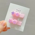 Detail van roze pompon haarclips met paarse bloem lovertjes op met lint omwikkelde basis - Roze Stijl